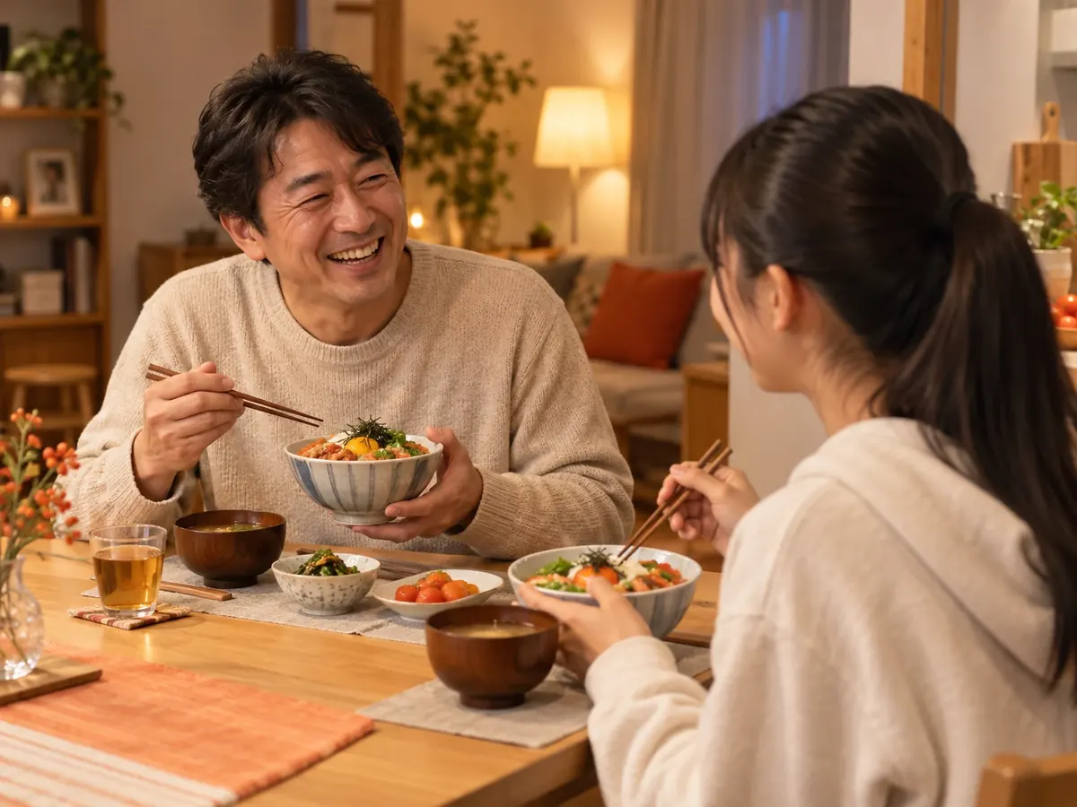 夜の食卓で、丼を手に笑い合う父と娘のイメージ